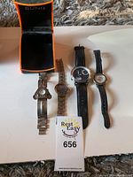 Four wrist watches laid out flat with a Sung watch box.