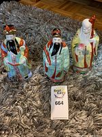 Three vintage colorful Chinese Sanxing God porcelain figurines placed on carpet.