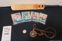 Signed cricket bat laid on surface with five football cards, 2012 Masters marker, and Canadian Olympics medal on leather string