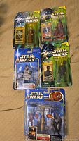 Six Star Wars action figures on green and blue backing cards in original blister pack packaging, displayed on a cloth.