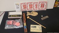 Lot overview with guitar strings, wooden wind instrument, tuner bar, metal finger pick, harmonica in box, and digital metronome.