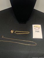 All three jewelry pieces displayed on black cloth with bust and lot tag