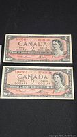 Two Canadian $2 bills from 1954 laid one above the other showing the full front design.