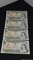 Four uncirculated Canadian 1 dollar bills from 1973 laid vertically