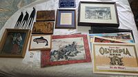 Photo of entire assortment laid on white surface including framed art, carvings, sculptures, and placemats.