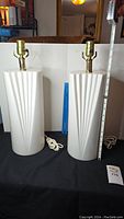 Pair of white ceramic lamps with vertical grooves on the base, brass bulb socket fittings on top, cords visible, measured at 18 inches tall with socket.