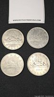 Four Canadian dollar coins dated 1965, 1968, and 1985, showing the classic voyageur canoe design.