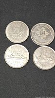 Four Canadian silver dollar coins displayed showing the front (obverse) side with the Canadian Coat of Arms and date 1958 on two coins, and the other two showcasing commemorative designs with Expo 67 and 1867-1967 Centennial.