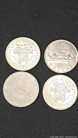 Four Canadian one dollar coins including two British Columbia commemorative dollars and two 1969 Canadian silver dollars.