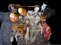 Full assortment of Halloween decorations including skeleton parts, jack-o'-lanterns, basket with scarecrow, severed hands, and witch hat with owl figure.