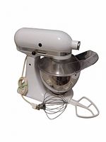 Full view of white KitchenAid mixer with bowl, whisk and flat beater on countertop