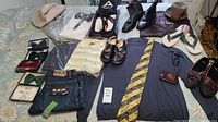 Full view of lot with shoes, shirts, ties, hats, and wallet laid out on bed