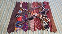 Full view of all 16 ties laid out flat showing various colors and patterns including floral and geometric designs.