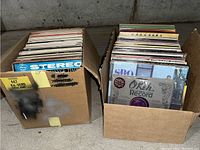 Two boxes filled with vinyl LP albums arranged vertically showing album spines and some cover fronts visible