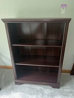 Front view of the 3-tier woodgrain veneer bookcase showing the three shelves within a simple rectangular frame.
