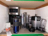 Braun coffee maker and Ninja blender along with travel mugs and other items on a shelf
