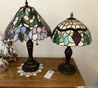 Both lamps displayed side by side on wood table, silver tea set beside them