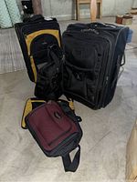 Photo showing two upright wheeled luggage pieces and one shoulder bag placed on a basement floor.