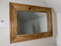 Front view of rectangular wood framed mirror mounted on wall.