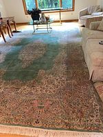 Full view of large oriental rug on hardwood floor under living room furniture showing overall pattern, color and condition.