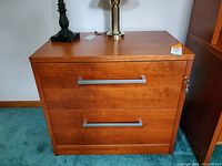 Front view of wooden Jesper 2-drawer file cabinet with silver handles and lock key visible on top drawer