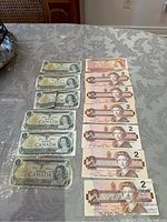 Photo showing six one-dollar Canadian banknotes and seven two-dollar Canadian banknotes laid out on a table.