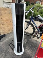 Front view of black and white tower air cooler with vertical vents.