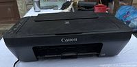Front view of Canon printer showing Canon logo and paper output area.