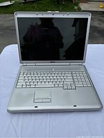 Front view of the Dell Inspiron 1720 laptop displaying the keyboard, touchpad, and screen in a silver chassis.