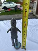 Front view of the standing stone sculpture showing full figure and blue crystal base with measuring tape indicating about 7 inches tall.