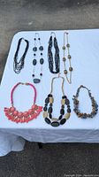 Photo of seven fashion jewelry pieces on white cloth - diverse necklaces and bracelet