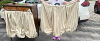 Two beige striped damask drapery panels held stretched to show size and fabric pattern, pleated bottom, Velcro attachment top edges visible