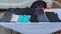 Image of assorted women's tops and tights laid out on a table, showing variety of colors and styles.