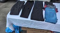Nine pairs of women's tights and jeggings in various colors laid out on a white tablecloth showing all items included in the lot