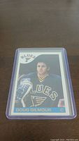 Front side of 1985-86 Topps Doug Gilmour hockey card in protective sleeve on a brown surface.