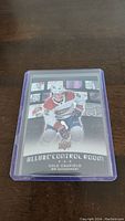 Front of the Cole Caufield Allure Control Room rookie hockey card in protective sleeve, showing player image and team logos.