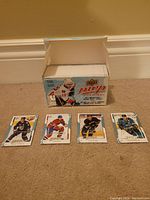 Photo of the open box of 2008/2009 Upper Deck MVP hockey cards placed on the floor with four loose cards fanned out in front of it.