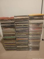Three tall stacks of over 110 music CDs, various titles and covers visible, mostly contemporary and Christian genres
