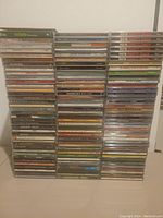 Photo showing 113 CDs stacked in multiple columns on a flat surface, spines showing various country, pop, rock, and easy listening music albums and compilations.