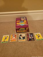 Closed and opened 1991 Score Baseball card box with 5 baseball cards displayed in front showing various player images and designs.