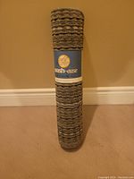 Rolled carpet runner with label showing brand Nash-ease, standing vertically against wall.