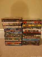 Photo of 39 DVDs stacked in two piles showing the variety of movie titles and genres.