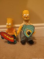 Bart and Homer Simpsons plush dolls holding themed cardboard props, standing on carpet against beige wall.