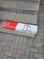 New in box Obmante sawhorse wrapped in plastic and cardboard packaging lying on pavement