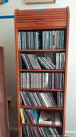 Full view of wooden roll-top CD shelf filled with multiple rows of CDs
