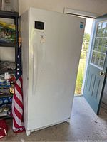 Full exterior front view of white upright freezer showing door handle and control panel area.