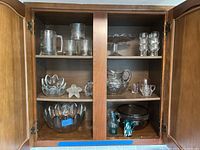 Cabinet with all glassware items arranged showing a variety of clear glass bowls, plates, pitchers, and glasses with different shapes.