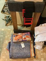 Photo of wooden furniture dolly with carpet padding and moving straps on top along with folded moving blanket and boxed moving straps
