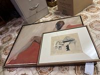 Framed painting and framed etching artwork shown together on floor.