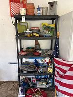 Photo of black plastic shelving unit with various gardening and garage items on shelves, showing condition and size.